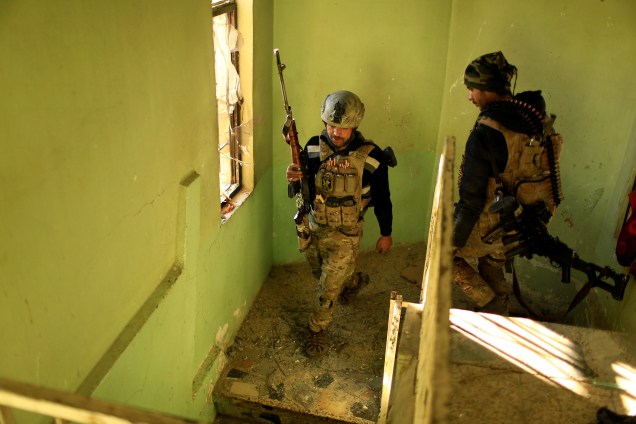 Integrantes das forças iraquianas caminham em um prédio durante a batalha contra militantes islâmicos no distrito de Mithaq, no leste de Mosul, no Iraque