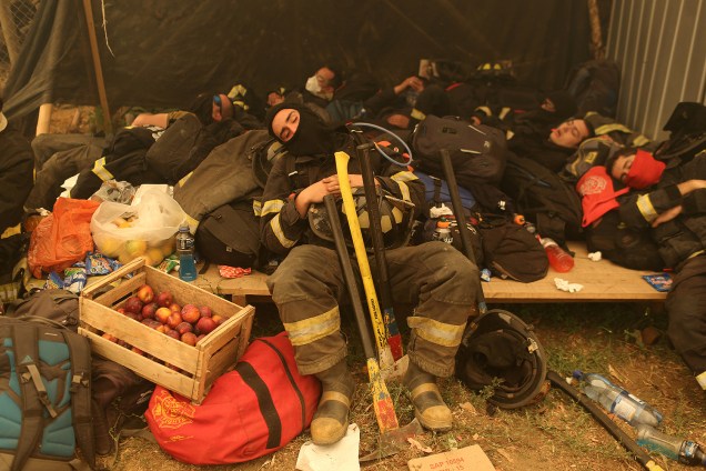 Bombeiros descansam durante um incêndio florestal em Santa Olga, no Chile. A presidente Michelle Bachelet declarou estado de emergência, enviou tropas e pediu ajuda internacional no que chamou do 'maior desastre florestal' da história do Chile - 27/01/2017