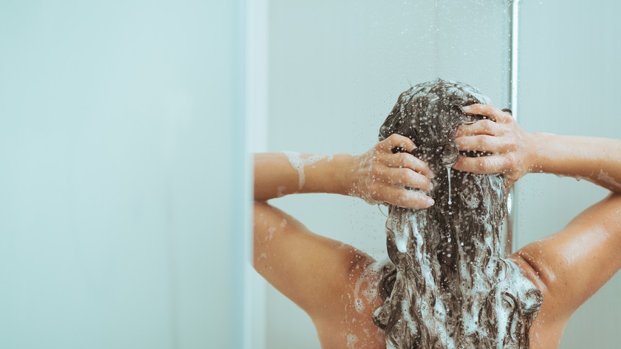 Jovem mulher Lavando cabeça com shampoo
