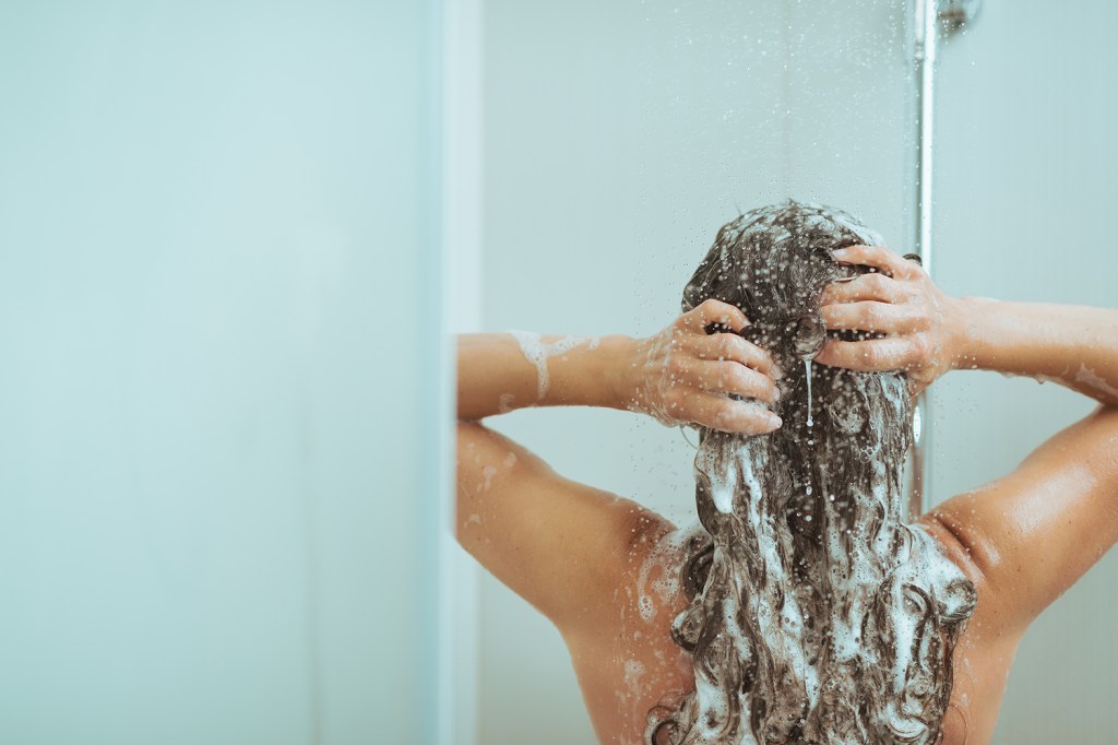 Jovem mulher Lavando cabeça com shampoo