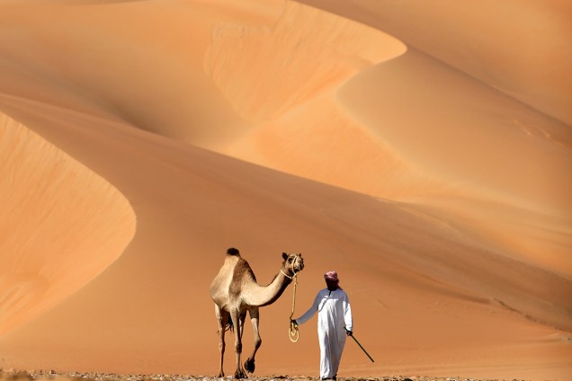 Homem caminha com seu camelo por entre dunas do deserto de Liwa, durante o festival anual de dunas Liwa Moreeb, nos Emirados Árabes