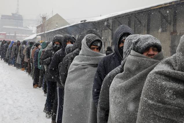 Refugiados e imigrantes estão morrendo na repentina onda de frio na Europa. Imigrantes aguardam na fila para receber um prato de comida em um armazém aduaneiro abandonado em Belgrado.