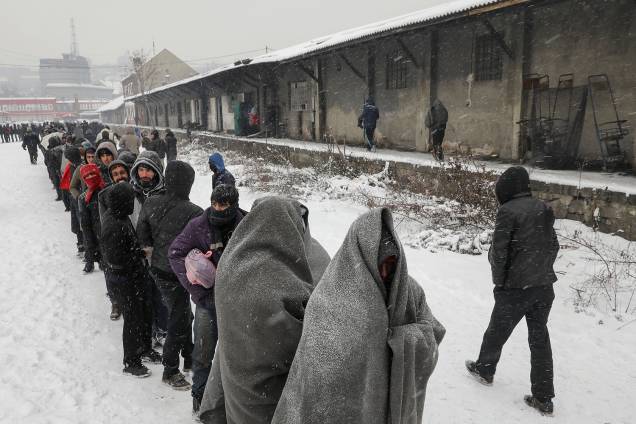 Refugiados e imigrantes estão morrendo na repentina onda de frio na Europa. Imigrantes aguardam na fila para receber um prato de comida em um armazém aduaneiro abandonado em Belgrado