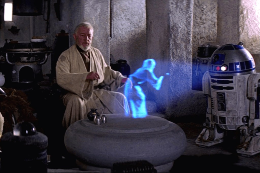 O robô R2D2 projeta um holograma, em cena de "Star Wars"
