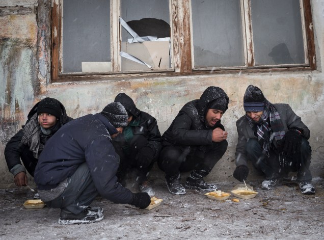 Imigrantes se alimentam do lado de fora de ujm armazém durante nevasca em Belgrado, Sérvia