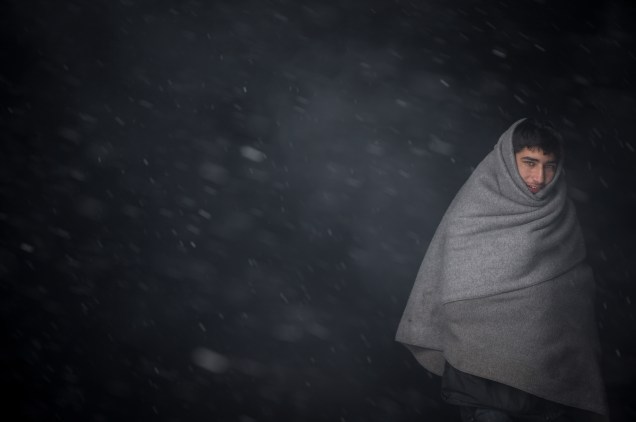 Imigrante se aquece com um cobertor durante forte nevasca em Belgrado, Sérvia