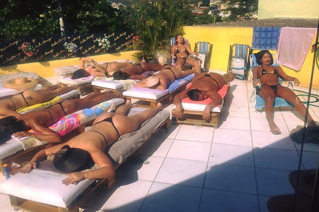 Mulheres tomam sol com fita isolante no ligar do biquíni, na laje de Érika Bronze, no Rio