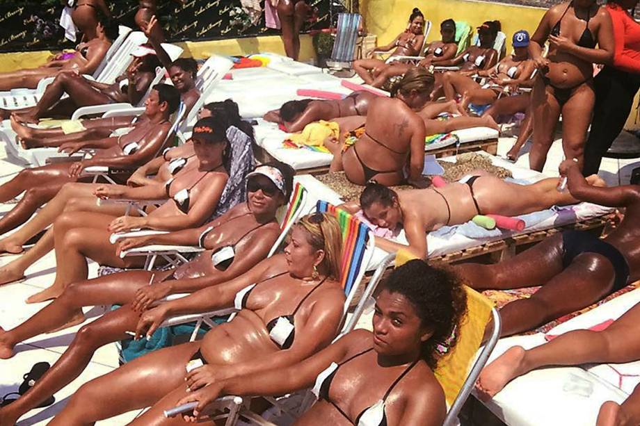 Mulheres tomam sol com fita isolante no ligar do biquíni, na laje de Érika Bronze, no Rio