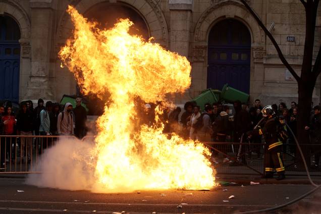 Bombeiro tenta apagar chamas iniciadas no protesto de estudantes contra a violência policial em Paris, França - 23/02/2017