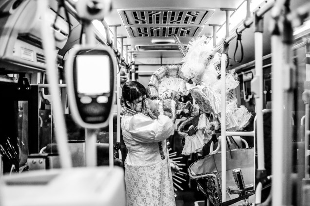 Ajudante carrega fantasias de carnaval para dentro do ônibus após desfile no Sambódromo Anhembi, em São Paulo