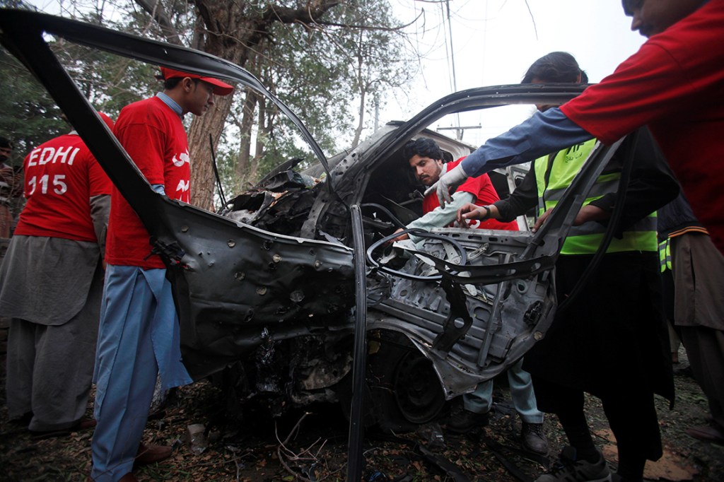 Voluntários trabalham no local onde carro-bomba explodiu na cidade de Peshawar, Paquistão