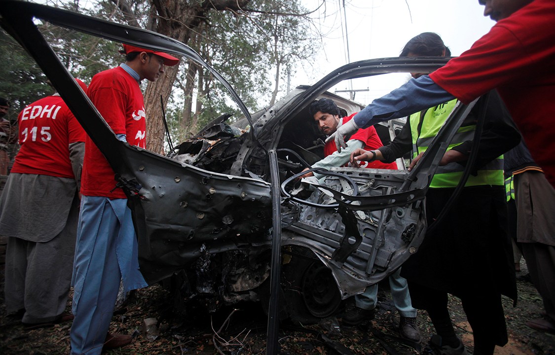 Voluntários trabalham no local onde carro-bomba explodiu na cidade de Peshawar, Paquistão