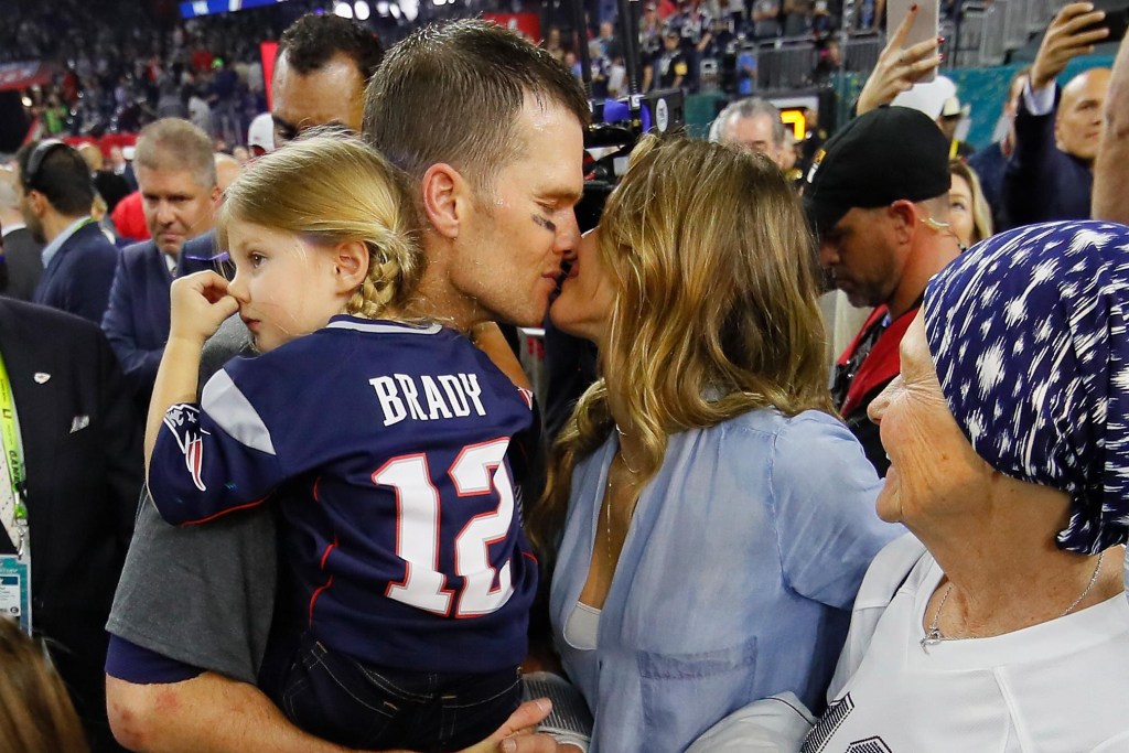 Com a filha do casal no colo, Tom Brady recebe um beijo da esposa Gisele Bündchen após o título do Super Bowl 2017