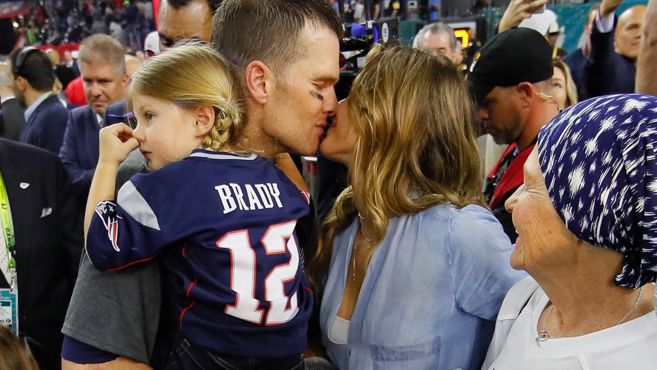 Com a filha do casal no colo, Tom Brady recebe um beijo da esposa Gisele Bündchen após o título do Super Bowl 2017