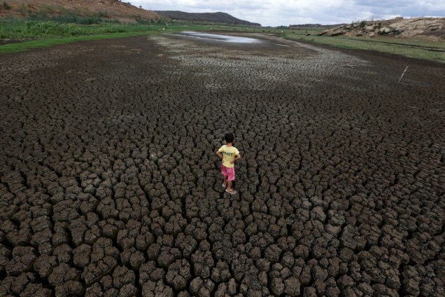 Natan Cabral, 5 anos, caminha sobre o solo rachado do reservatório de Boqueirão, na região metropolitana de Campina Grande, Paraíba
