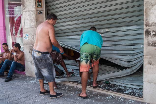 Homens consertam uma porta de loja após ataque de assaltantes em Vila Velha, no Espírito Santo - 06/02/2017
