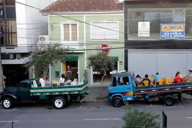 Clientes sentam em caminhões estacionados em frente ao restaurante em Caxias do Sul