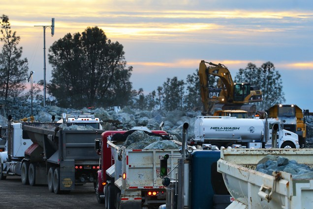 Caminhões levam pedras para reparar o solo próximo ao escoadouro de emergência da barragem de Oroville, Califórnia, na tentativa de evitar o rompimento do sistema de contenção da represa - 13/02/2017