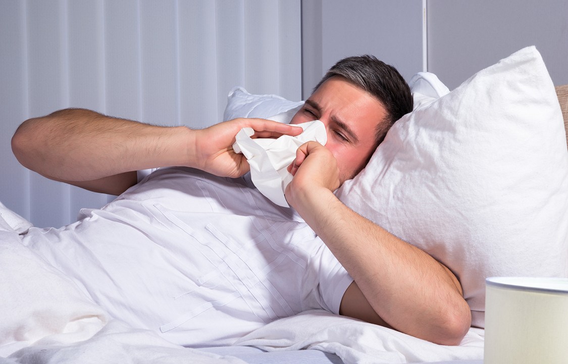 Man Infected With Cold And Flu Blowing His Nose In Tissue Paper