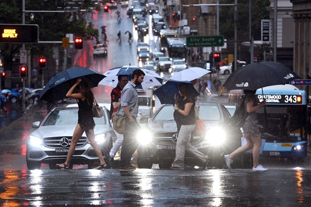 Pessoas caminham com guarda-chuvas abertos em dia chuvoso na cidade de Sidney, Austrália - 17/02/2017