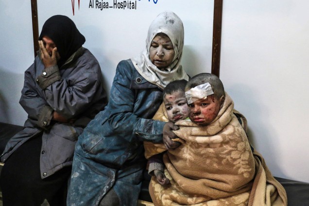 Mulher é fotografada com crianças feridas em um hospital após um ataque no distrito rebelde de Barzah, no subúrbio de Damasco, na Síria - 20/02/2017