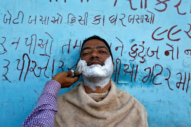 Homem faz a barba em uma estrada na cidade de Ahmedabad, na Índia - 27/02/2017