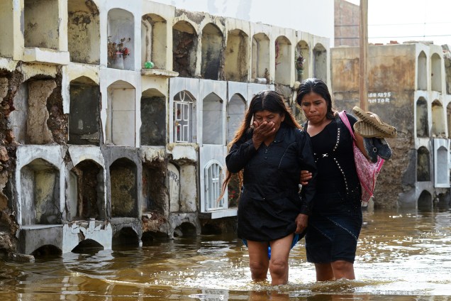Mulheres atravessam área alagada no cemitério de Tucume, no Peru, para participar de um funeral. Chuvas torrenciais, deslizamentos e transbordamentos de rios já deixaram 25 mortos e afetaram mais de 200 mil pessoas no país desde o início do ano - 07/02/2017