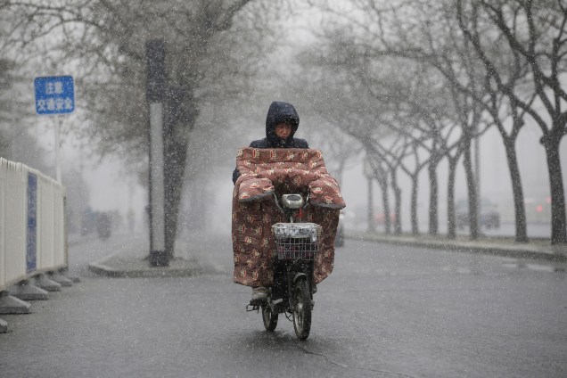 Mulher conduz uma bicicleta elétrica durante uma nevasca em Pequim, na China - 21/02/2017 Jason Lee