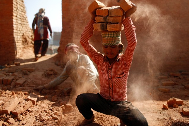 Trabalhador empilha tijolos em sua cabeça em uma olaria em Lalitpur, Nepal - 07/02/2017