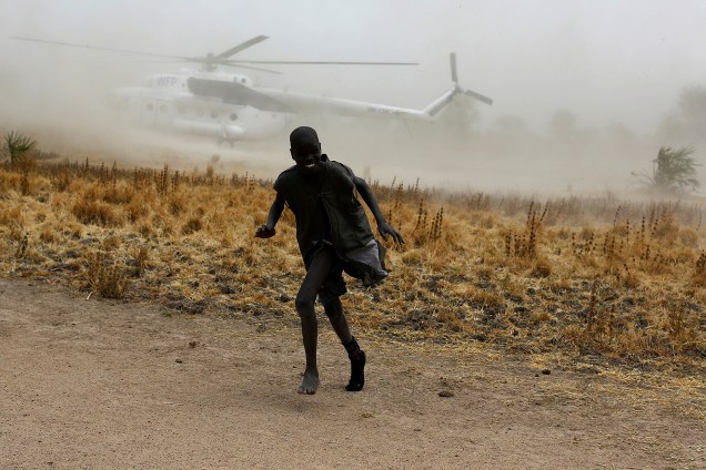Menino se afasta de um helicóptero do Programa Mundial de Alimentos das Nações Unidas (PAM) que aterrissa na vila de Rubkuai, no sul do Sudão, em imagem divulgada nesta segunda-feira (20)