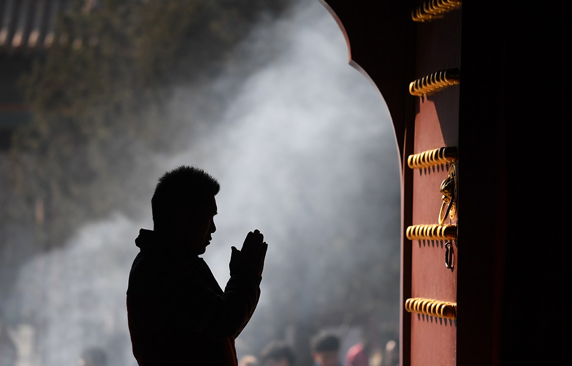 Homem reza no primeiro dia do ano tibetano, no templo de Yonghegong Lama, em Pequim