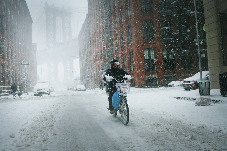 Um entregador atravessa a neve com sua bicicleta -09/02/2017