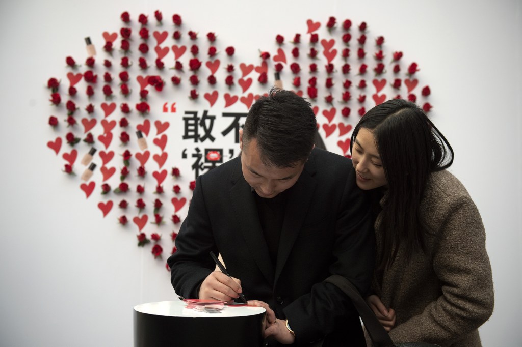 Casal de namorados escrevem em um cartão em formato de coração para comemorar o dia de São Valentim, "Valentine's Day", em Pequim