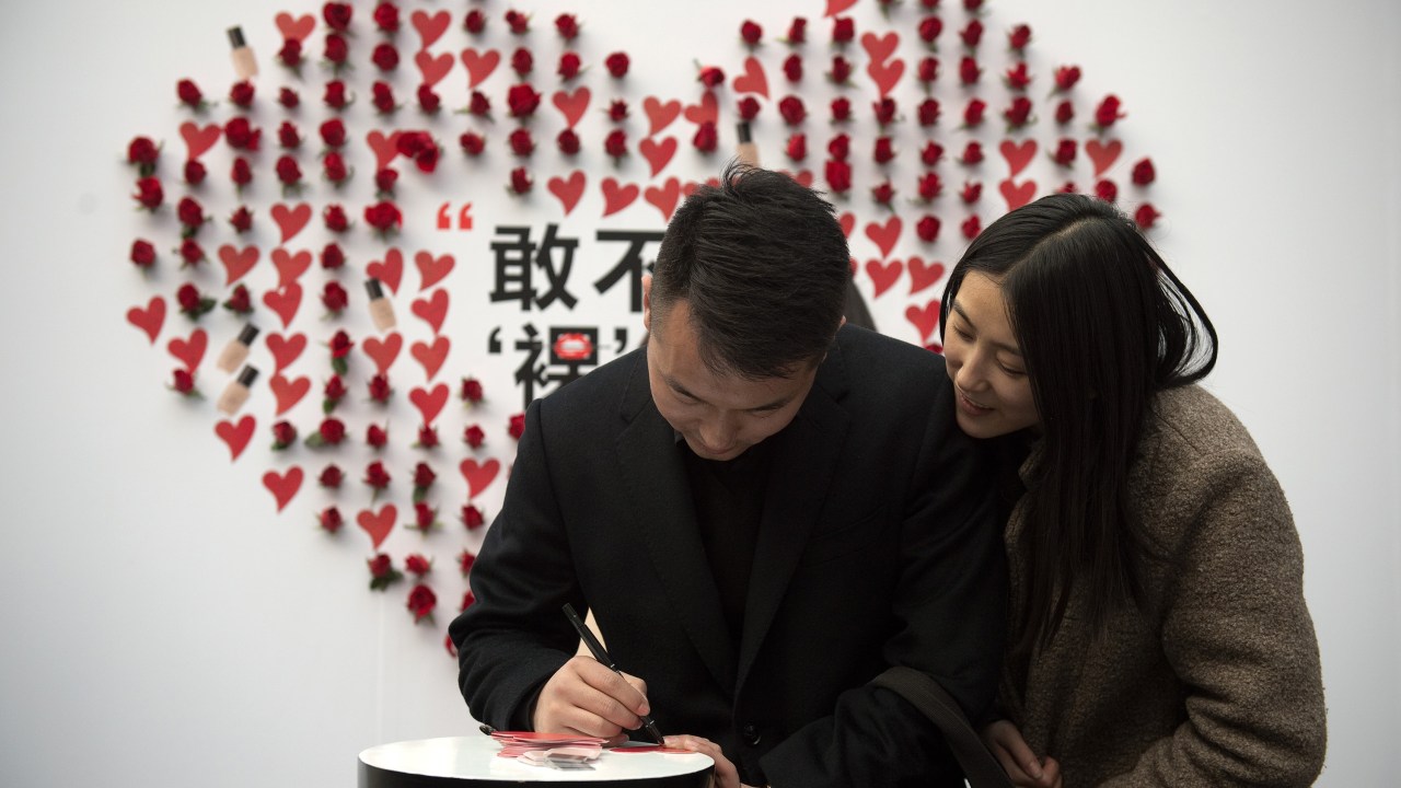 Casal de namorados escrevem em um cartão em formato de coração para comemorar o dia de São Valentim, "Valentine's Day", em Pequim