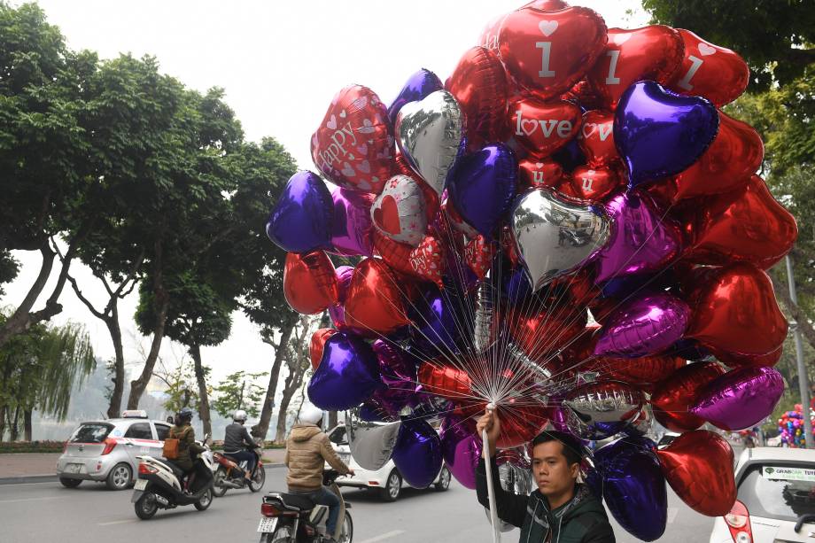 Vendedor caminha com balões em formato de coração no dia de São Valentim
