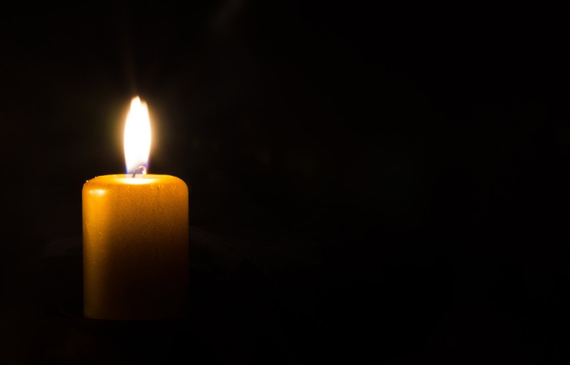 one burning candle decoration against black background