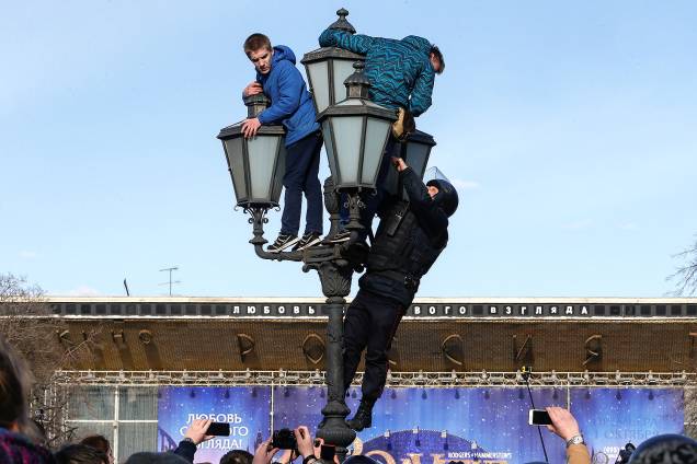 Policial escala poste de luz para conter manifestantes da oposição russa durante protesto em Moscou - 26/03/2017