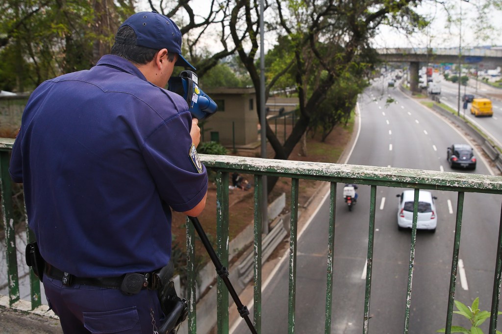 Agente da GCM fiscaliza com radar de mão a velocidade das motos na pista local da marginal Tietê