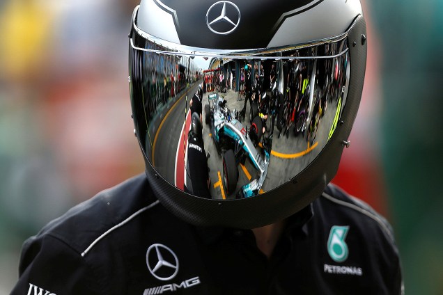 O finlandês Valtteri Bottas da Mercedes aparece refletido no capacete de um mecânico durante o treino de sexta-feira (24)