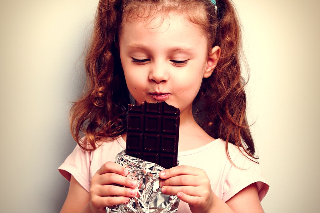 Menina criança comendo barra de chocolate