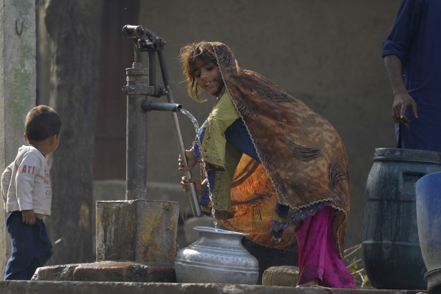 Menina enche um pote com água em uma fonte pública nos arredores de Lahore, no Paquistão - 21/03/2017