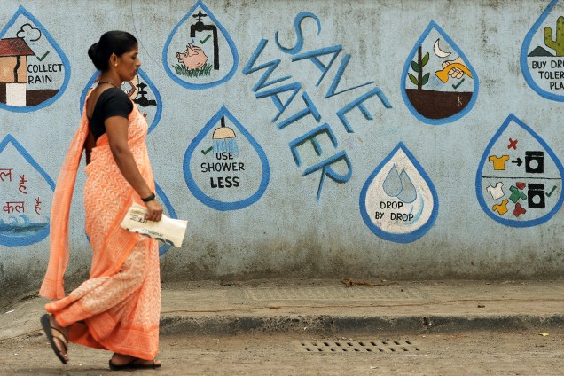 Mulher passa por uma parede adornada com mensagens de conservação de água em Mumbai na Índia - 22/03/2017