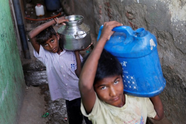 Meninos carregam recipientes com a água em uma favela de Mumbai, na India - 22/03/2017