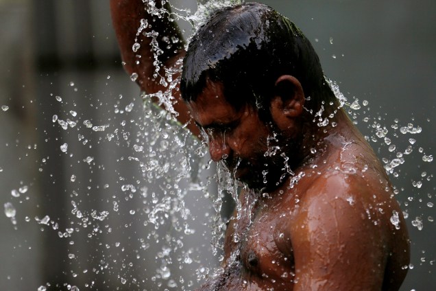 Homem se banha em um poço público em Colombo, no Sri Lanka - 22/03/2017