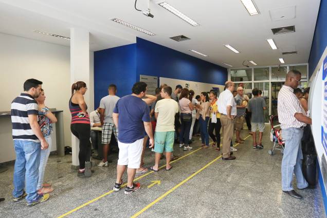 Pessoas formam filas nos caixas eletrônicos de agência da Caixa Econômica Federal, em São Paulo, para saque do FGTS