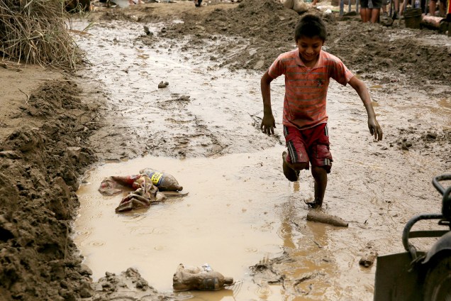 Criança atravessa uma poça de lama em Lima no Peru, após o fenômeno <span>"el niño costero"</span> causar enchentes e deslizamentos - 19/03/2017