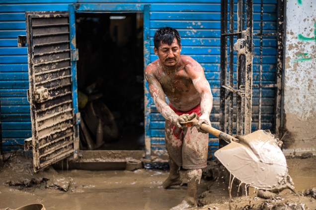 Morador de um distrito em Lima, Peru, remove lama de sua casa - 19/03/2017