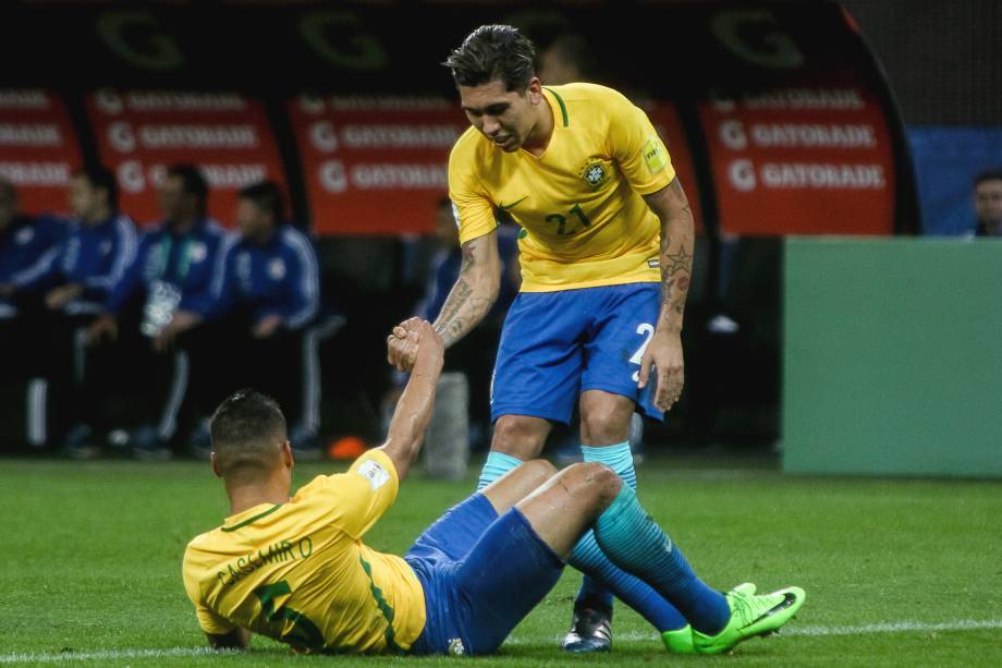 Firmino ajuda Casemiro a se levantar após jogada dura com a defesa paraguaia