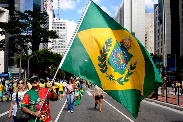 Na Avenida Paulista, um manifestante levanta a bandeira da monarquia durante o protesto organizado pelos movimentos sociais MBL (Movimento Brasil Livre) e "Vem Pra Rua", que também aconteceu em outras cidades do Brasil