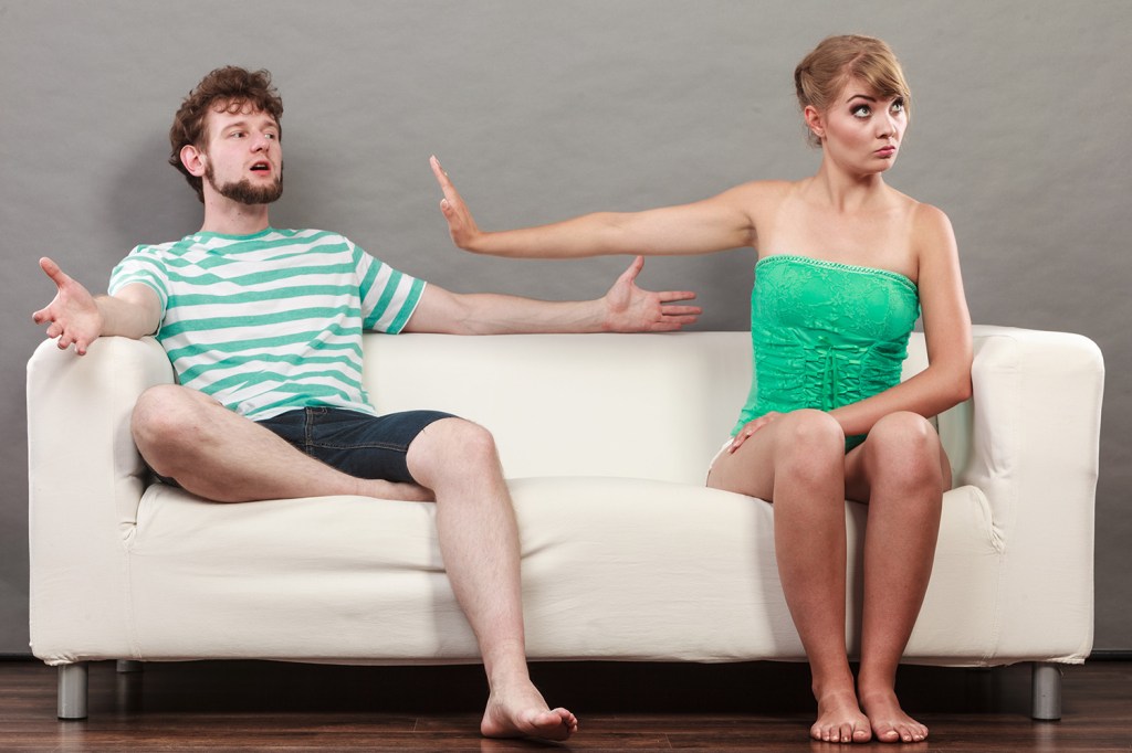Casal, mulher e homem, discutem no sofá